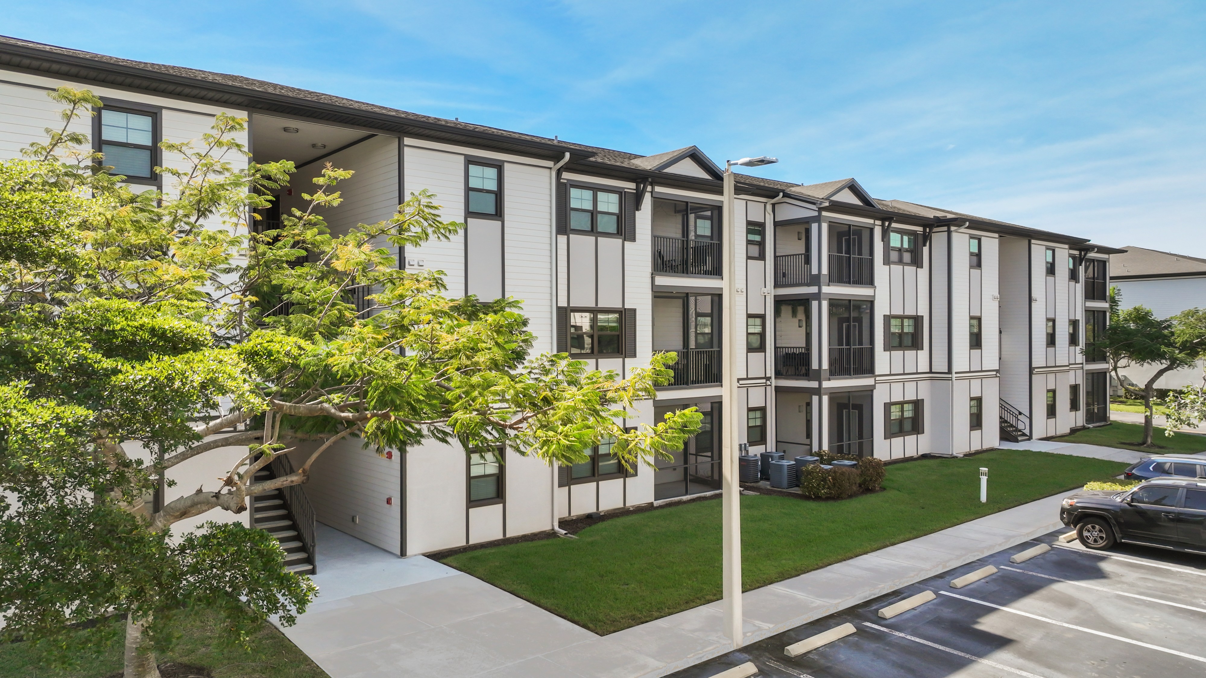 A modern apartment building with a parking lot in front.